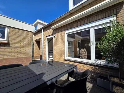 a wooden table and chairs in front of a house at Beach 44 in Egmond aan Zee
