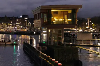 a house on the water near a river at night at SWEETS - Oosterdoksdraaibrug in Amsterdam