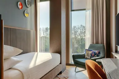 a bedroom with a bed and a chair and a window at Corendon Amsterdam New-West, a Tribute Portfolio Hotel in Amsterdam