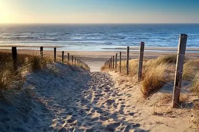a wooden fence on a beach near the ocean at Torensduin aan zee in Egmond aan Zee