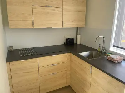 a kitchen with wooden cabinets and a sink at Torensduin aan zee in Egmond aan Zee