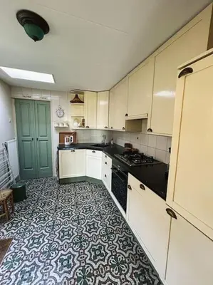 a kitchen with white cabinets and a tile floor at Onder de Kastanje! in Koedijk