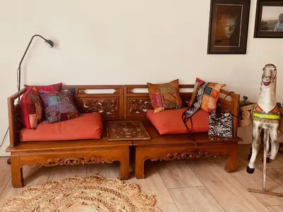 a living room with a wooden couch with pillows at Stunning Island Home with African Asian Vibe in Oude Meer