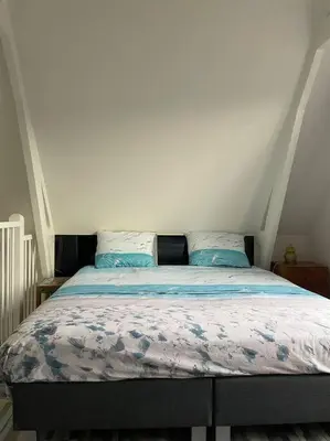 a bedroom with a bed with blue sheets at Wijk aan Zee de Wilde Roos in Wijk aan Zee