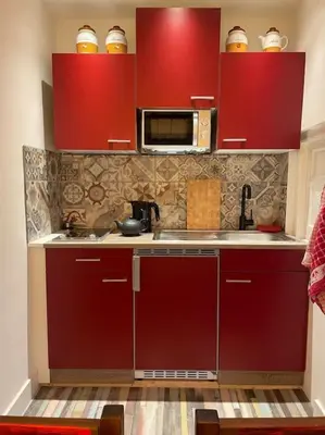 a kitchen with red cabinets and a microwave at Wijk aan Zee de Wilde Roos in Wijk aan Zee