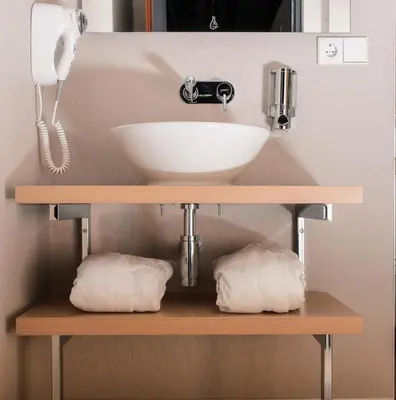 a bathroom with a sink and towels on a shelf at Amadi Panorama Hotel in Amsterdam
