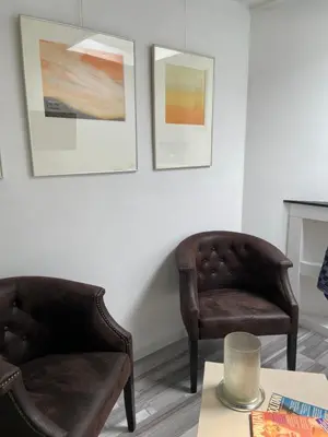 two chairs and a table in a room with paintings at Studio Bergen in Bergen