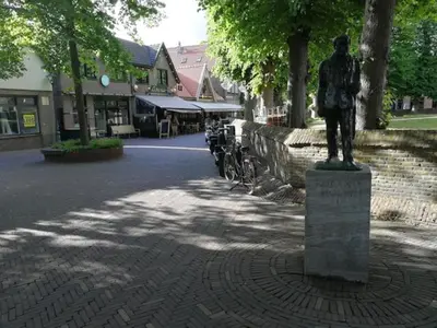 a statue of a man sitting on top of a sidewalk at Studio Bergen in Bergen