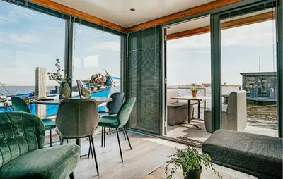 a living room with a table and chairs and windows at Havenlodge in Uitgeest