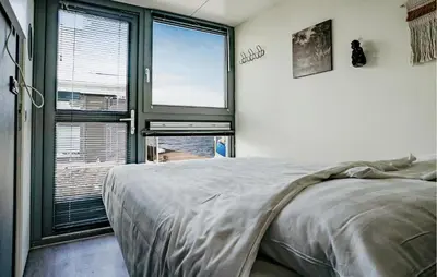 a bedroom with a bed and a large window at Havenlodge in Uitgeest