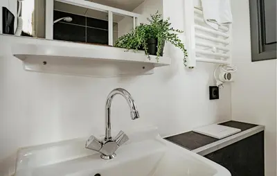 a white sink in a bathroom with a plant on a shelf at Havenlodge in Uitgeest