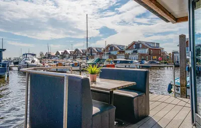 a table and chairs on a dock with boats in the water at Havenlodge in Uitgeest
