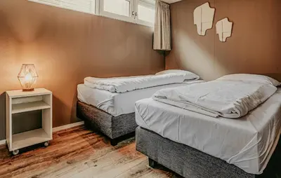 two twin beds in a room with a night stand at Woude in Uitgeest
