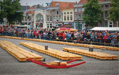 a crowd of people watching a parade with inflatable hot dogs at Woude in Uitgeest