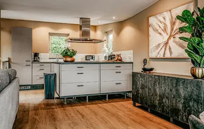 an open kitchen with white cabinets and a couch at Woude in Uitgeest