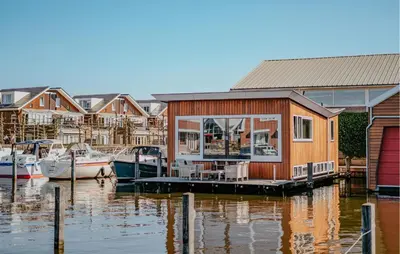 a house on a dock on the water with boats at Woude in Uitgeest