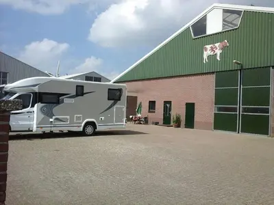 an rv parked next to a building with a dog on the roof at Boerderij Appartement Jachtlust in Voorhout