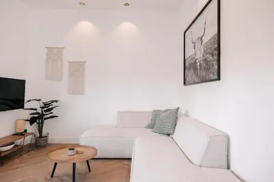 a white living room with a white couch and a table at Bella Beach House in Zandvoort