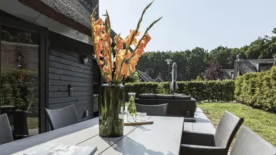 a vase filled with flowers sitting on a table at Dutchen Villapark Mooi Schoorl in Schoorl
