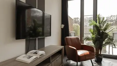 a living room with a television and a chair at Dutchen Villapark Mooi Schoorl in Schoorl