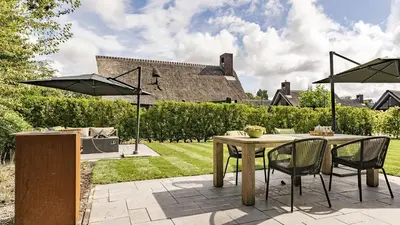 a patio with a table and chairs and umbrellas at Dutchen Villapark Mooi Schoorl in Schoorl
