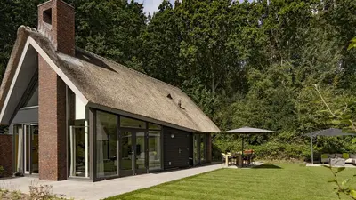 a house with a thatched roof and a garden at Dutchen Villapark Mooi Schoorl in Schoorl
