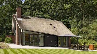 a house with a roof with a table and an umbrella at Dutchen Villapark Mooi Schoorl in Schoorl