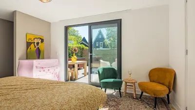 a bedroom with a bed and chairs and a table at Emma's Atelier in Bergen