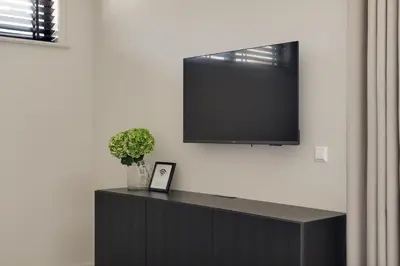 a black cabinet with a television on a wall at The Ville in Groet