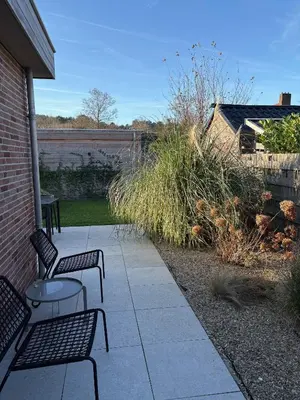a patio with two benches and a brick wall at The Ville in Groet