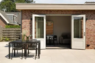 a patio with a table and chairs and a building at The Ville in Groet