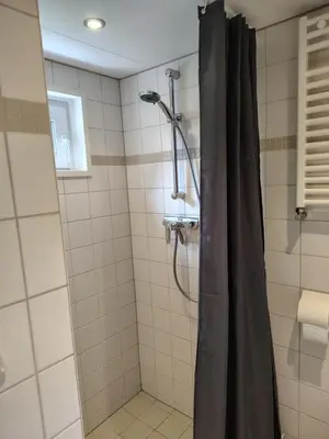 a shower with a black shower curtain in a bathroom at Rekerlanden 6 in Warmenhuizen