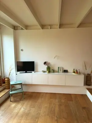 a living room with white cabinets and a tv at Rekerlanden 6 in Warmenhuizen