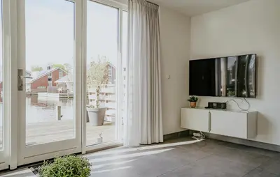 a living room with a tv and a large window at Westergeest Luxe in Uitgeest