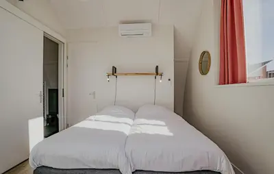 a bedroom with a bed with white sheets at Saskerlei in Uitgeest