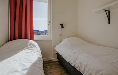 a small bedroom with two beds and a window at Saskerlei in Uitgeest