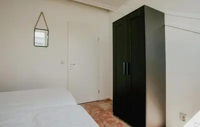 a bedroom with a black cabinet next to a bed at Oostergeest 3 6P in Uitgeest