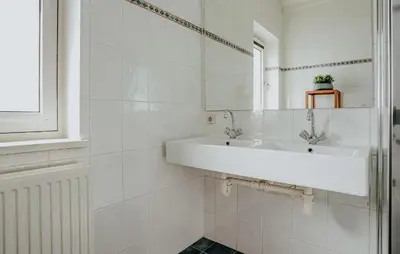 a white bathroom with a sink and a mirror at Oostergeest 3 6P in Uitgeest