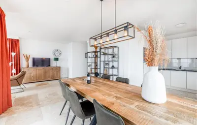 a dining room with a table with chairs and a vase at Appartement Crab in Egmond aan Zee