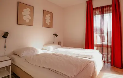 two beds in a bedroom with red curtains at Appartement Crab in Egmond aan Zee