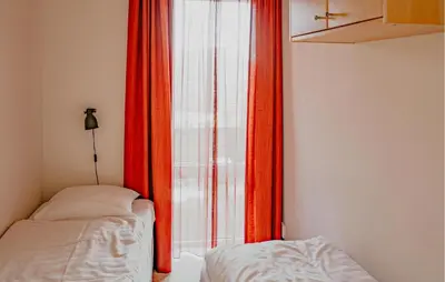 a bedroom with red curtains and a bed next to a window at Appartement Crab in Egmond aan Zee