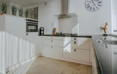 a kitchen with white cabinets and a clock on the wall at Shrimp in Egmond aan Zee