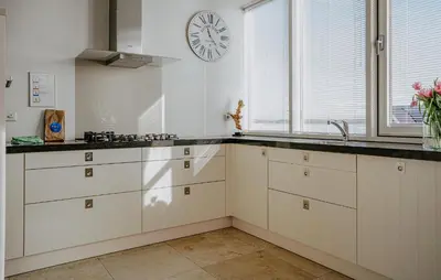 a kitchen with white cabinets and a clock on the wall at Shrimp in Egmond aan Zee