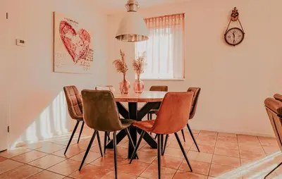 a dining room table with chairs and a clock on the wall at Westergeest 3 6P in Uitgeest