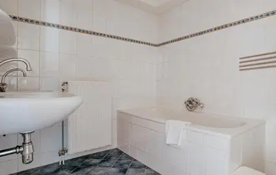 a white bathroom with a sink and a tub at Westergeest 3 6P in Uitgeest
