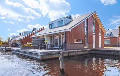 a house on a dock next to a body of water at Busch & Dam in Uitgeest