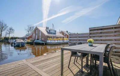 a wooden deck with a table and chairs next to the water at Busch & Dam in Uitgeest