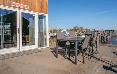 a table and chairs on a patio with a view of the water at Kraaijennest in Uitgeest