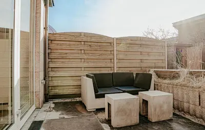 a couch sitting on a patio with two tables at Sea Bass in Egmond aan Zee