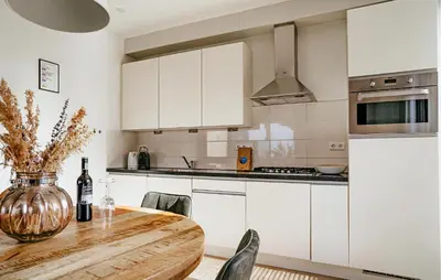 a kitchen with white cabinets and a wooden table at Sea Bass in Egmond aan Zee